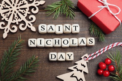 Photo of Cubes with phrase Saint Nicholas Day, gift box and festive decor on wooden table, flat lay