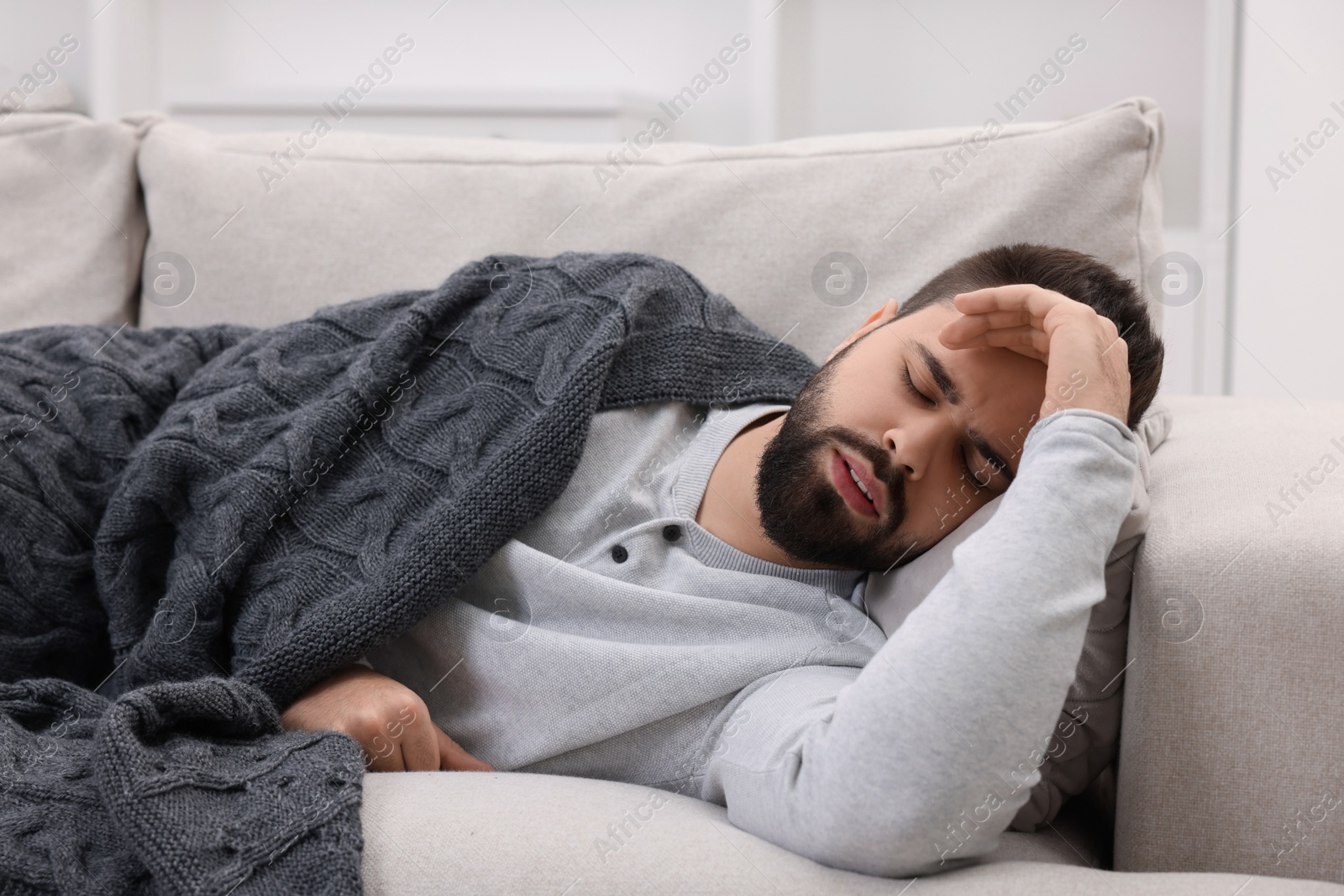 Photo of Man suffering from headache on sofa at home