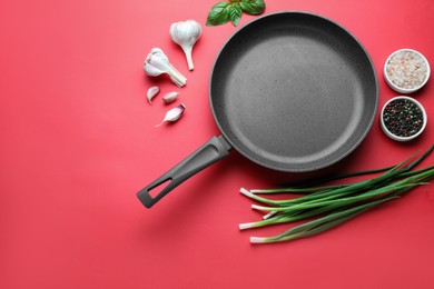 Flat lay composition with frying pan and fresh products on red background, space for text