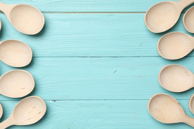 Photo of New wooden spoons on light blue wooden table, flat lay with space for text. Cooking utensils