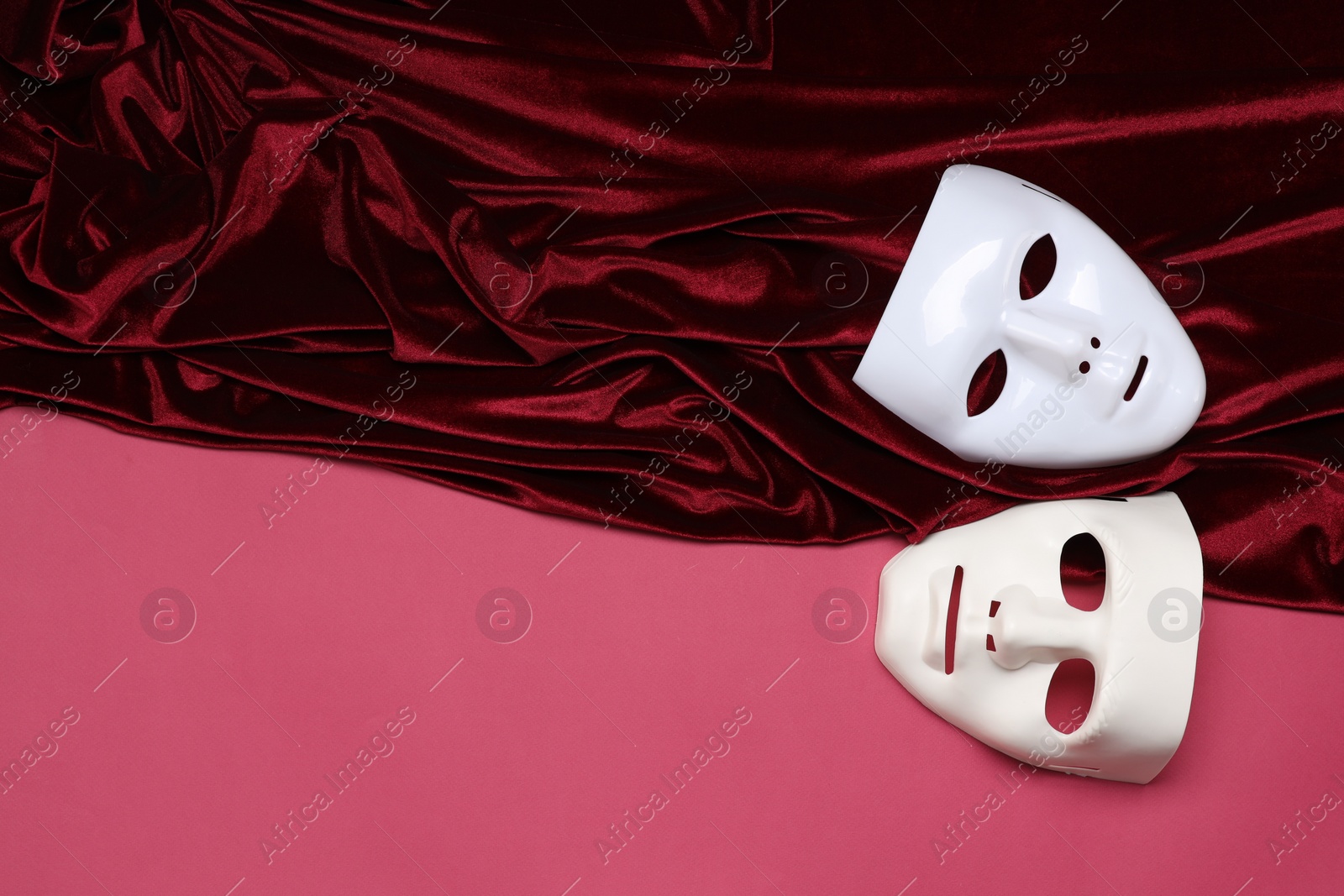 Photo of Theater arts. White masks and red fabric on pink background, top view. Space for text