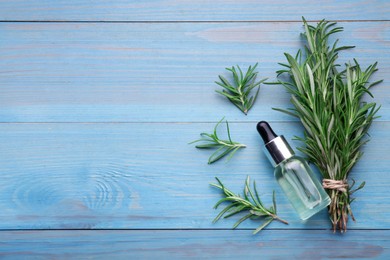 Photo of Bottle of rosemary essential oil and sprigs on light blue wooden table, flat lay. Space for text