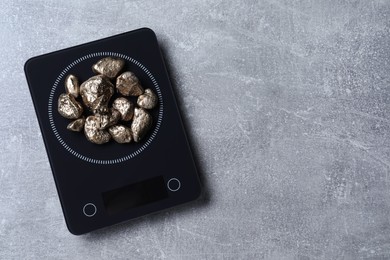 Photo of Digital scales with gold nuggets on light grey table, top view. Space for text