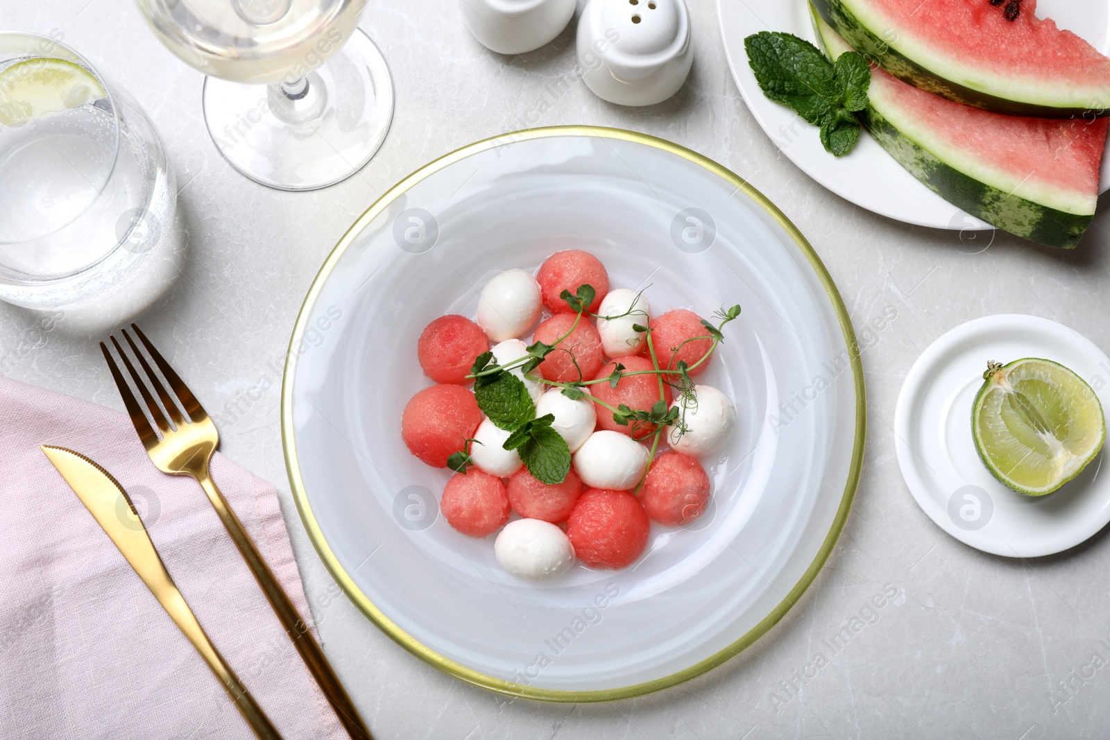 Photo of Delicious salad with watermelon balls, herbs and mozzarella cheese served on light table, flat lay