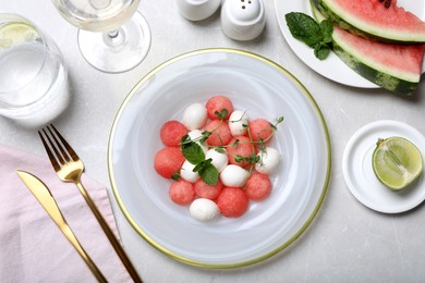 Photo of Delicious salad with watermelon balls, herbs and mozzarella cheese served on light table, flat lay