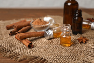 Photo of Bottles with cinnamon oil, powder and sticks on table