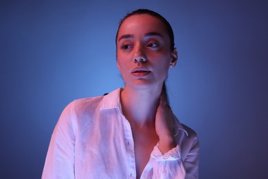 Photo of Portrait of beautiful young woman posing on blue background with neon lights