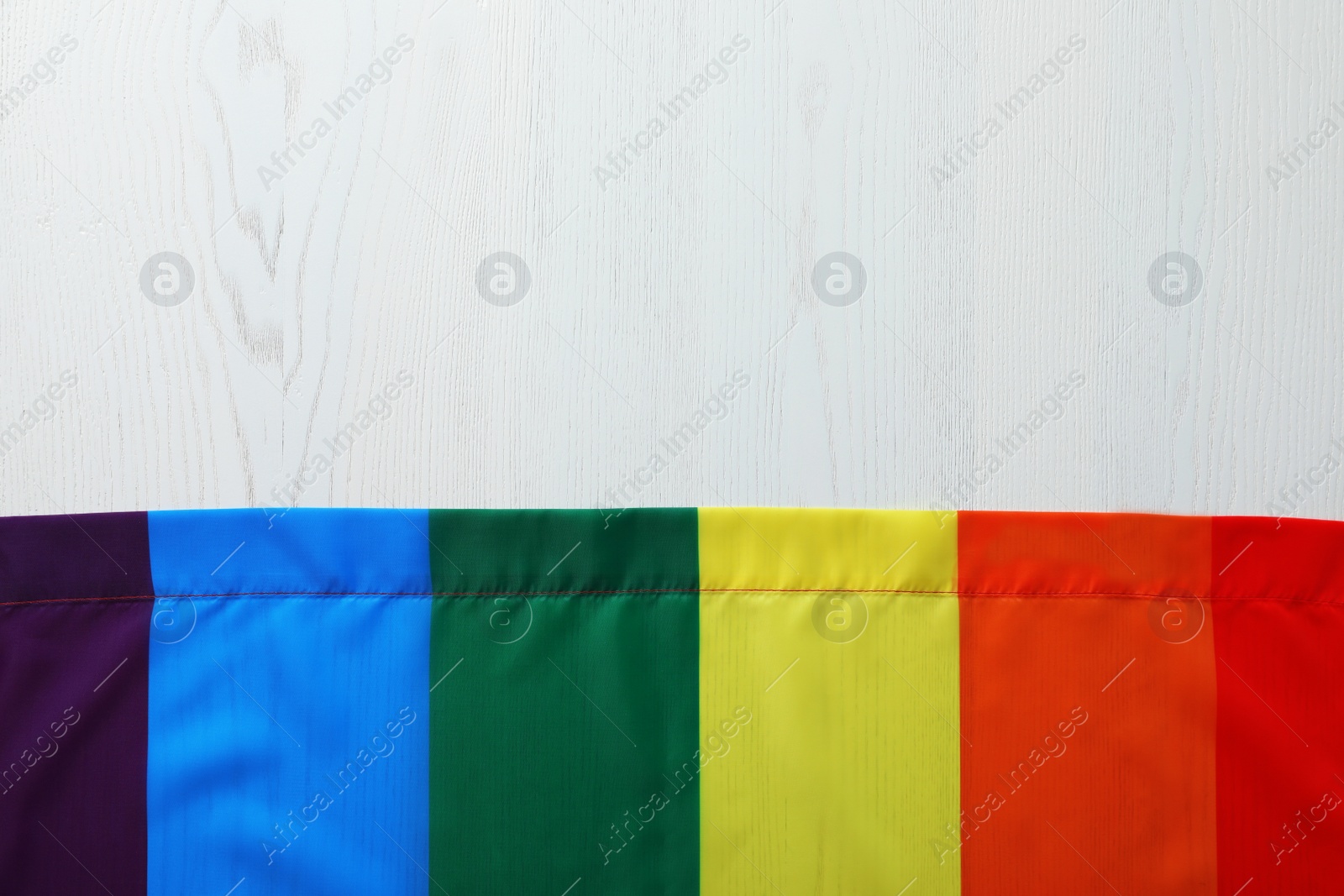 Photo of Rainbow gay flag on wooden background, top view with space for text. LGBT concept