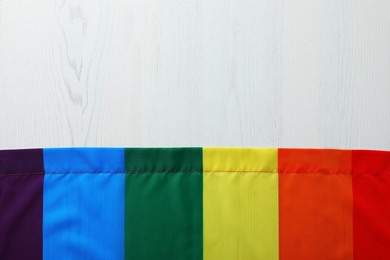 Photo of Rainbow gay flag on wooden background, top view with space for text. LGBT concept