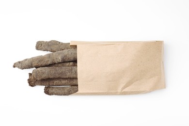 Paper bag with raw salsify roots on white background, top view