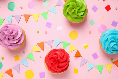 Photo of Colorful birthday cupcakes on light pink background, flat lay