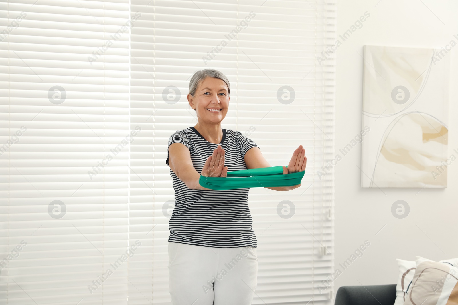 Photo of Senior woman doing exercise with fitness elastic band at home
