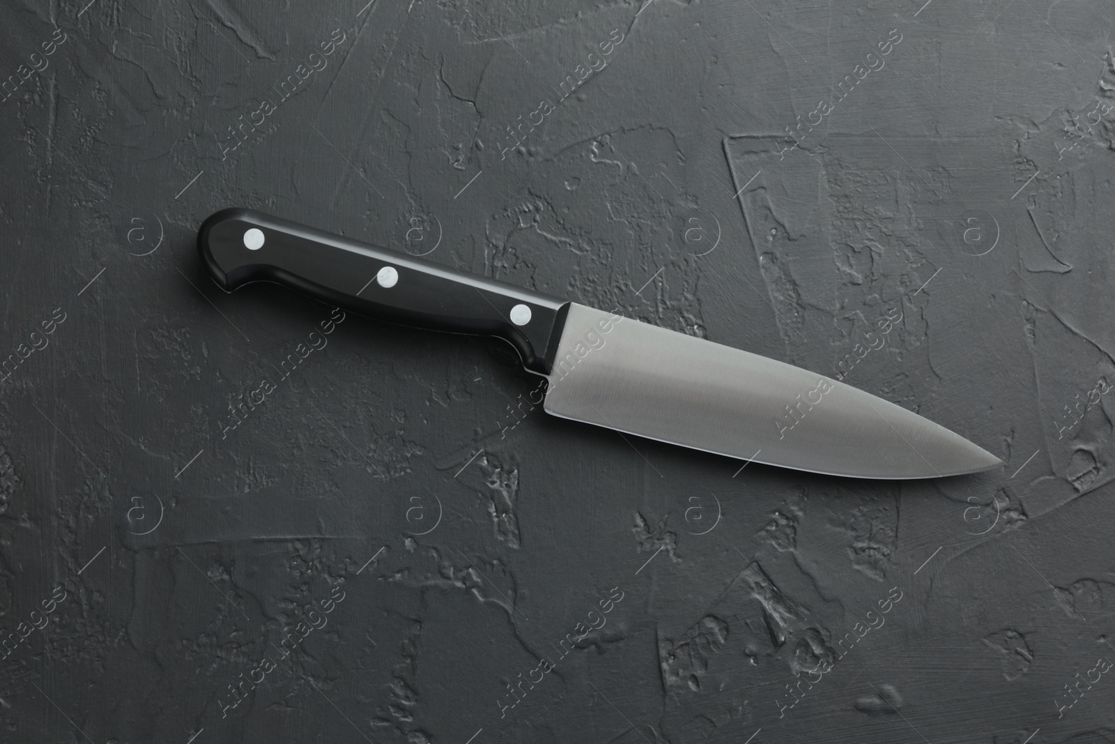 Photo of One sharp knife on dark textured table, top view