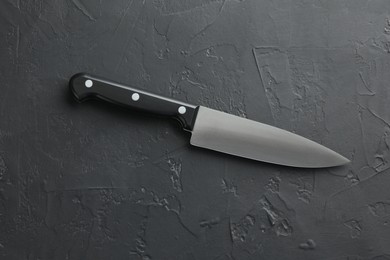 One sharp knife on dark textured table, top view