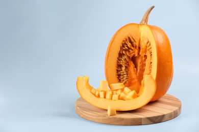 Cut fresh ripe pumpkin on light background, space for text