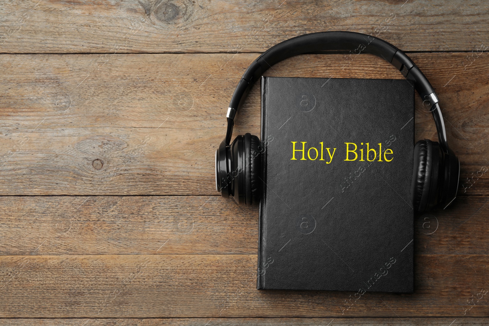 Photo of Bible and headphones on wooden background, top view with space for text. Religious audiobook