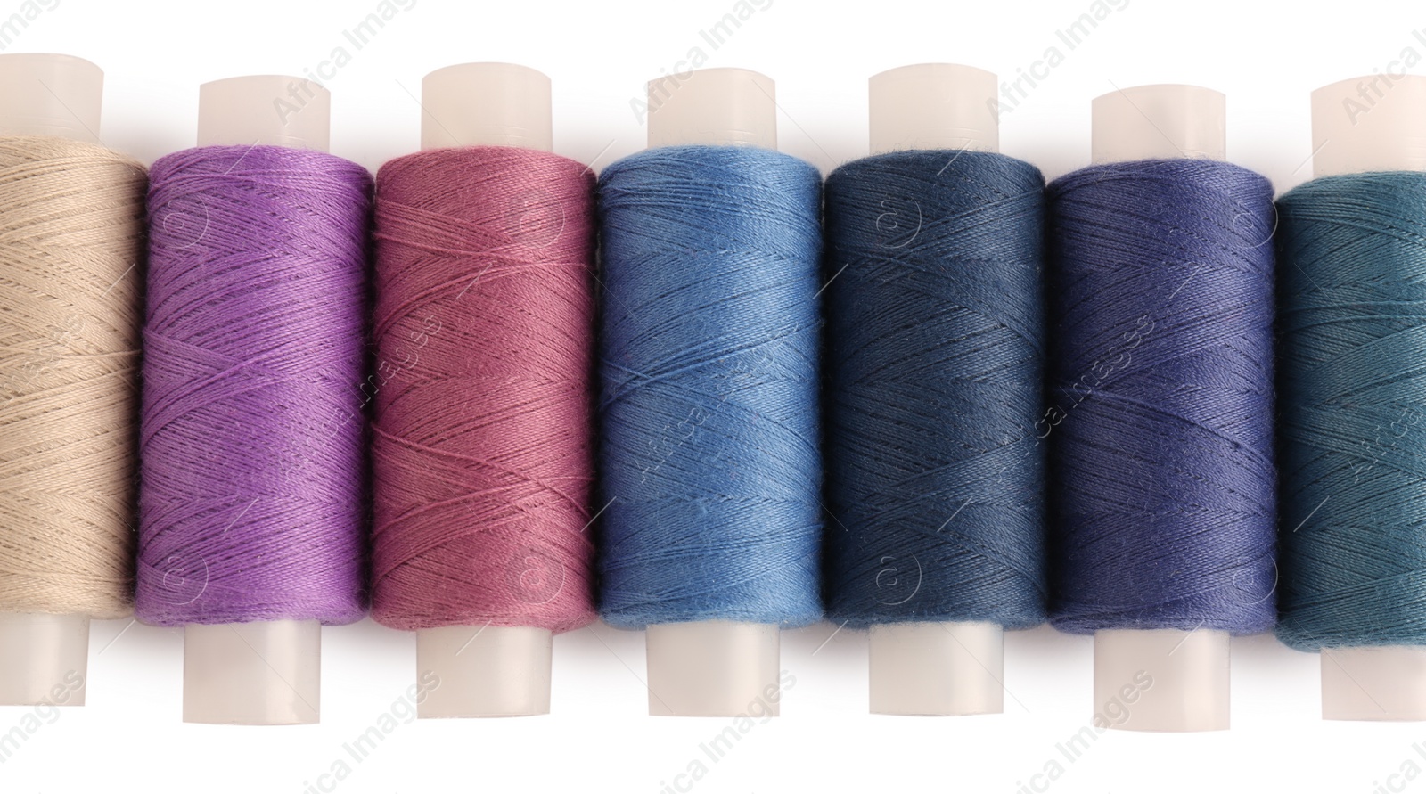 Photo of Set of colorful sewing threads on white background, top view