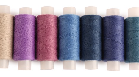 Photo of Set of colorful sewing threads on white background, top view