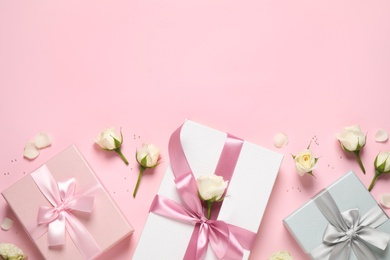 Photo of Elegant gift boxes and beautiful flowers on pink background, flat lay. Space for text