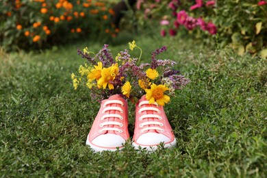 Photo of Shoes with beautiful flowers on grass outdoors