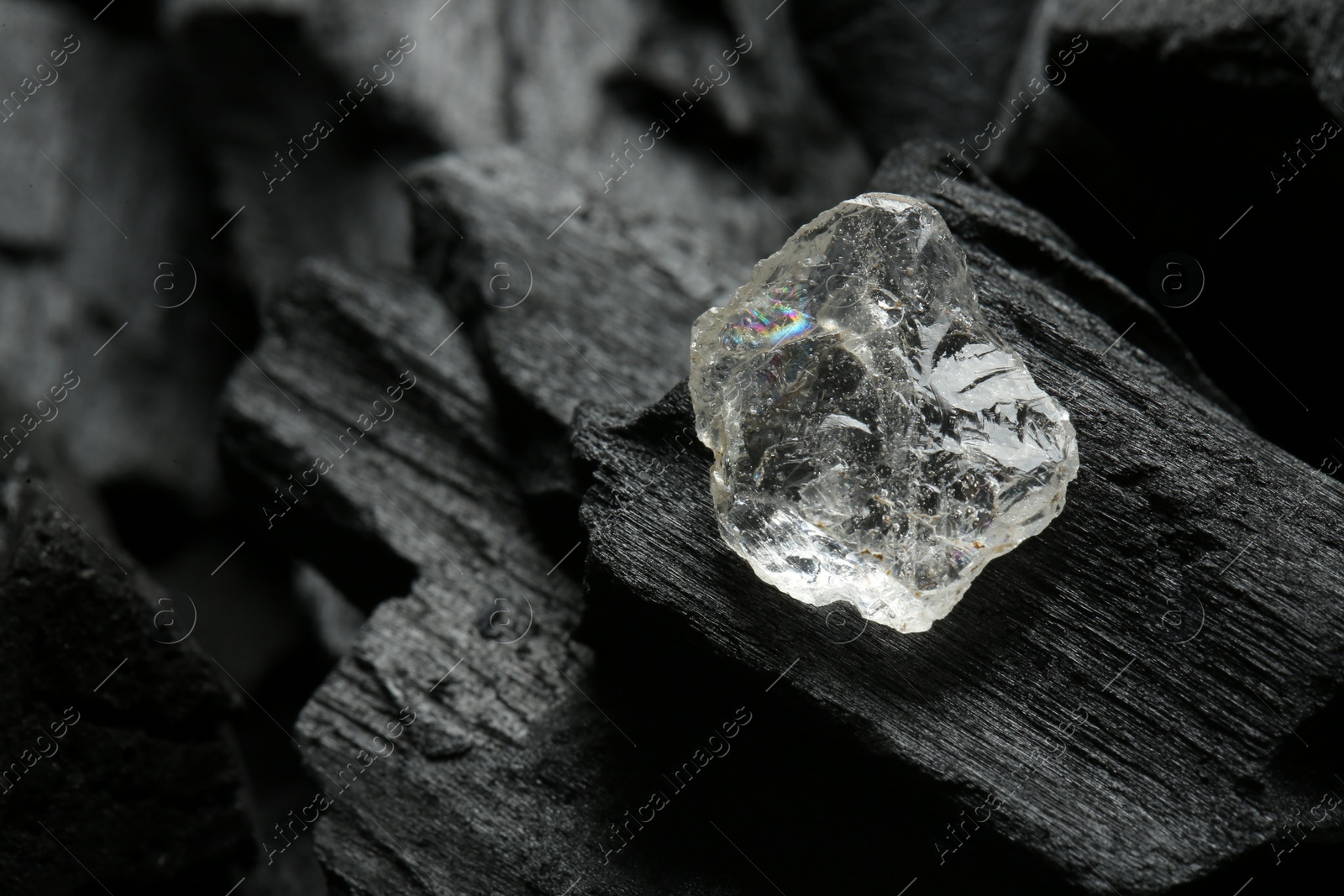 Photo of Beautiful shiny diamond on coal, closeup. Space for text