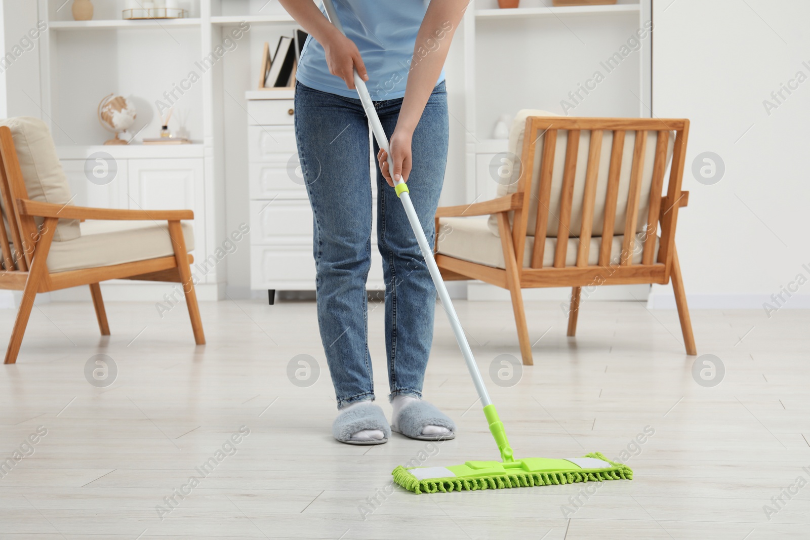 Photo of Woman cleaning dirty white parquet floor with mop at home, closeup