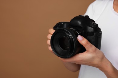 Photographer with camera on brown background, closeup. Space for text