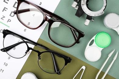Flat lay composition with vision test chart and glasses on color background