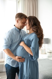 Photo of Pregnant woman with her husband in bedroom. Happy young family