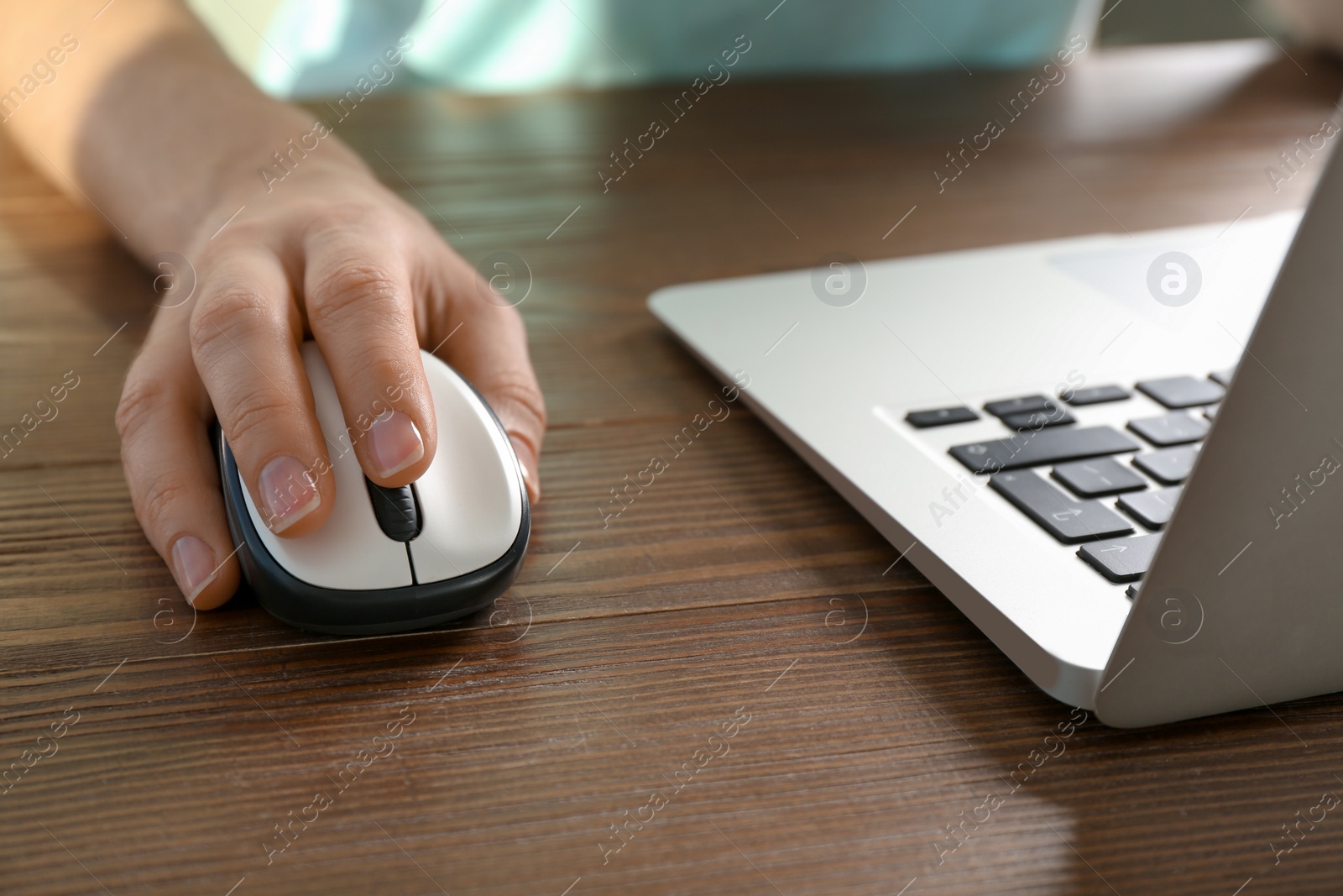 Photo of Woman using computer mouse with laptop at table, closeup