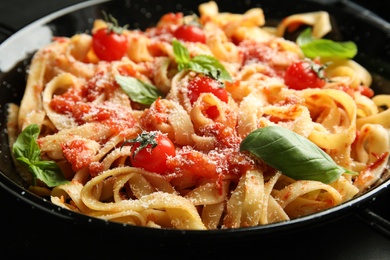 Tasty pasta with basil and tomato sauce on table, closeup