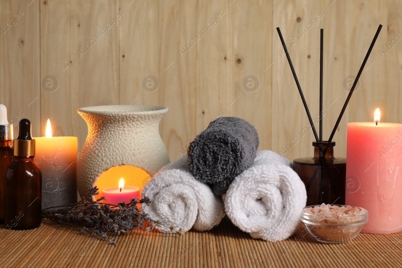 Photo of Aromatherapy. Scented candles, bottles, lavender, towels and sea salt on bamboo mat