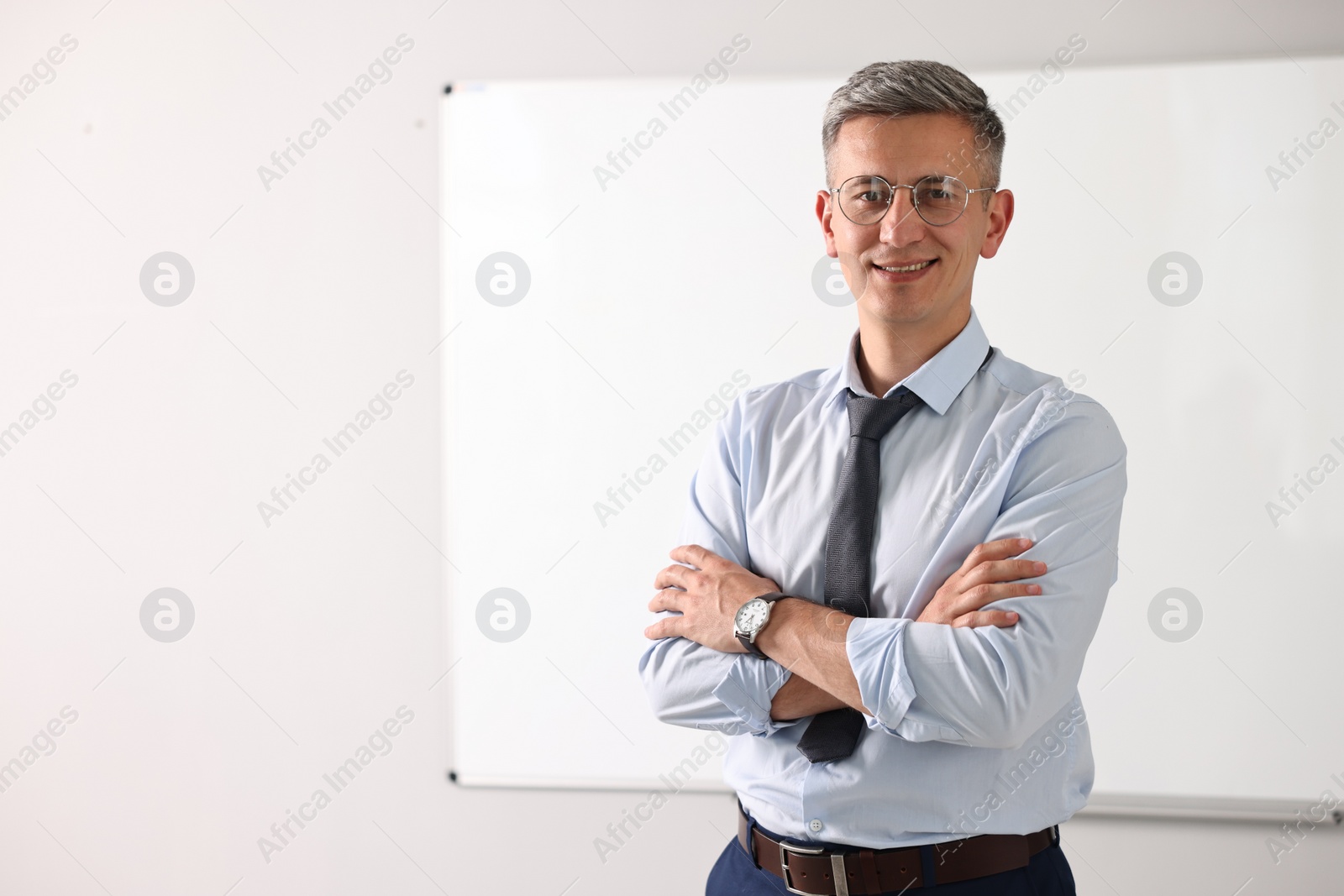 Photo of Teacher near whiteboard in classroom, space for text