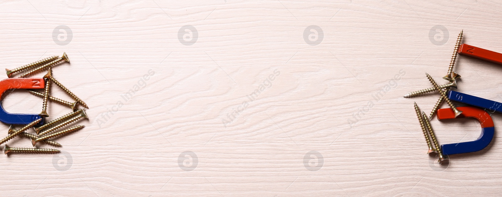 Photo of Magnets attracting screws on light wooden background, flat lay. Space for text