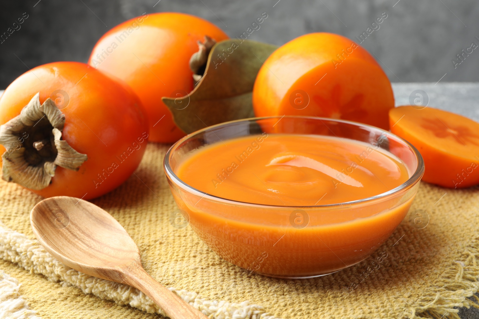 Photo of Delicious persimmon jam in glass bowl served on table