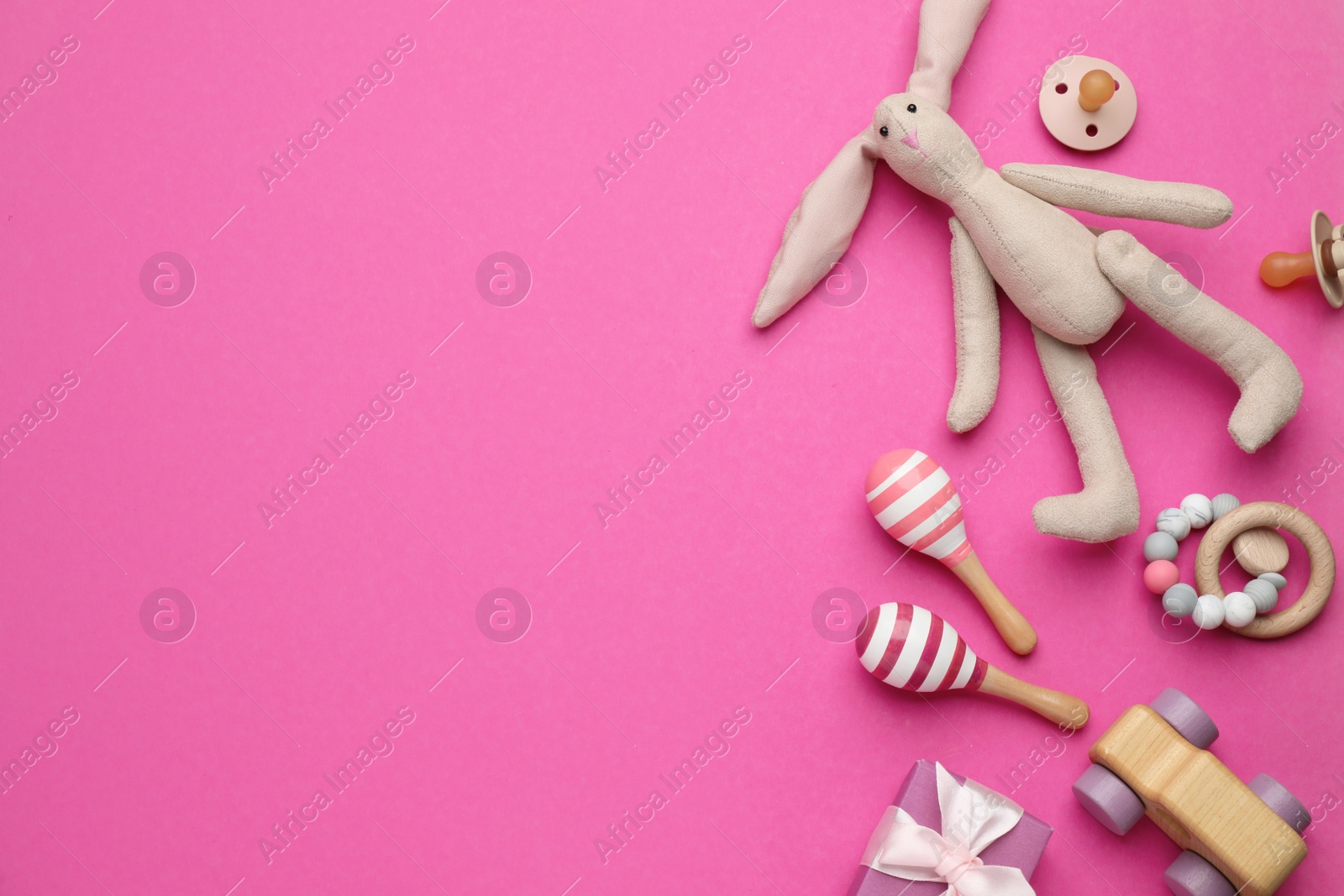 Photo of Gift box, pacifier and baby toys on pink background, flat lay. Space for text