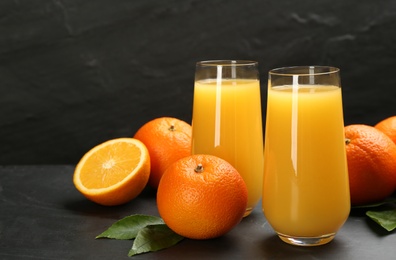 Photo of Delicious orange juice and fresh fruits on black table