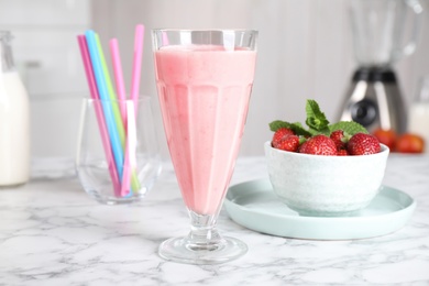 Photo of Tasty milk shake and strawberries on white marble table