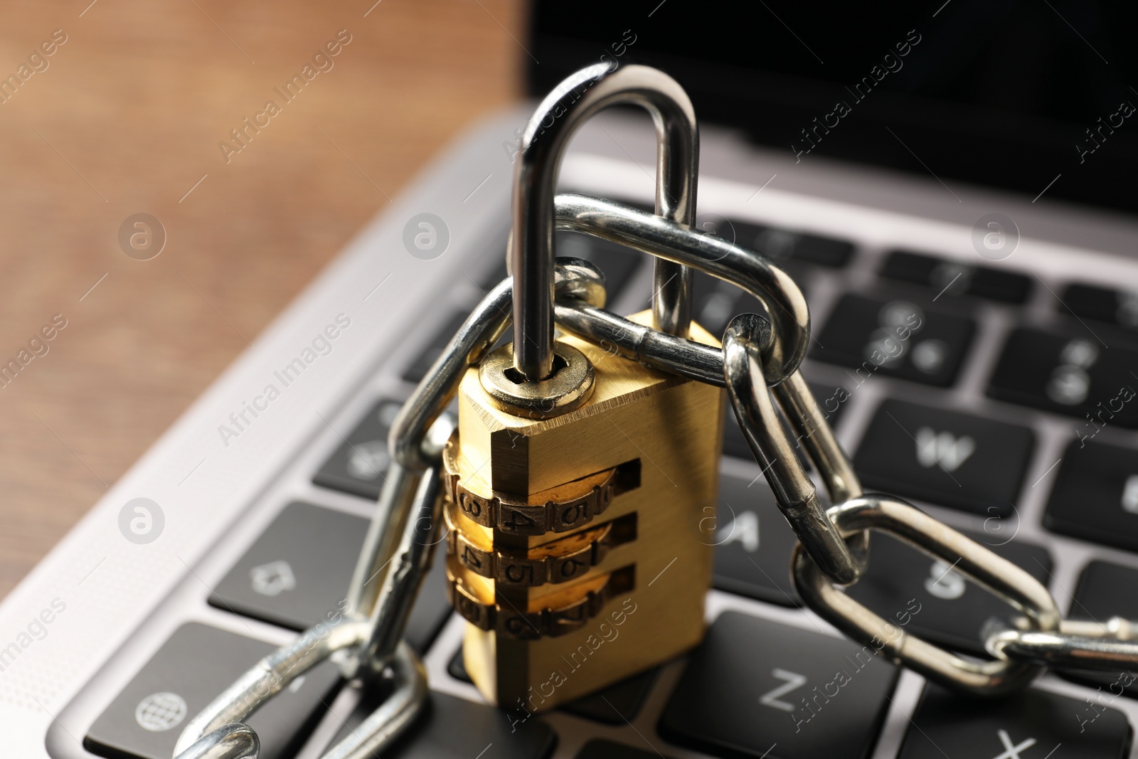 Photo of Cyber security. Laptop with padlock and chain on table, closeup