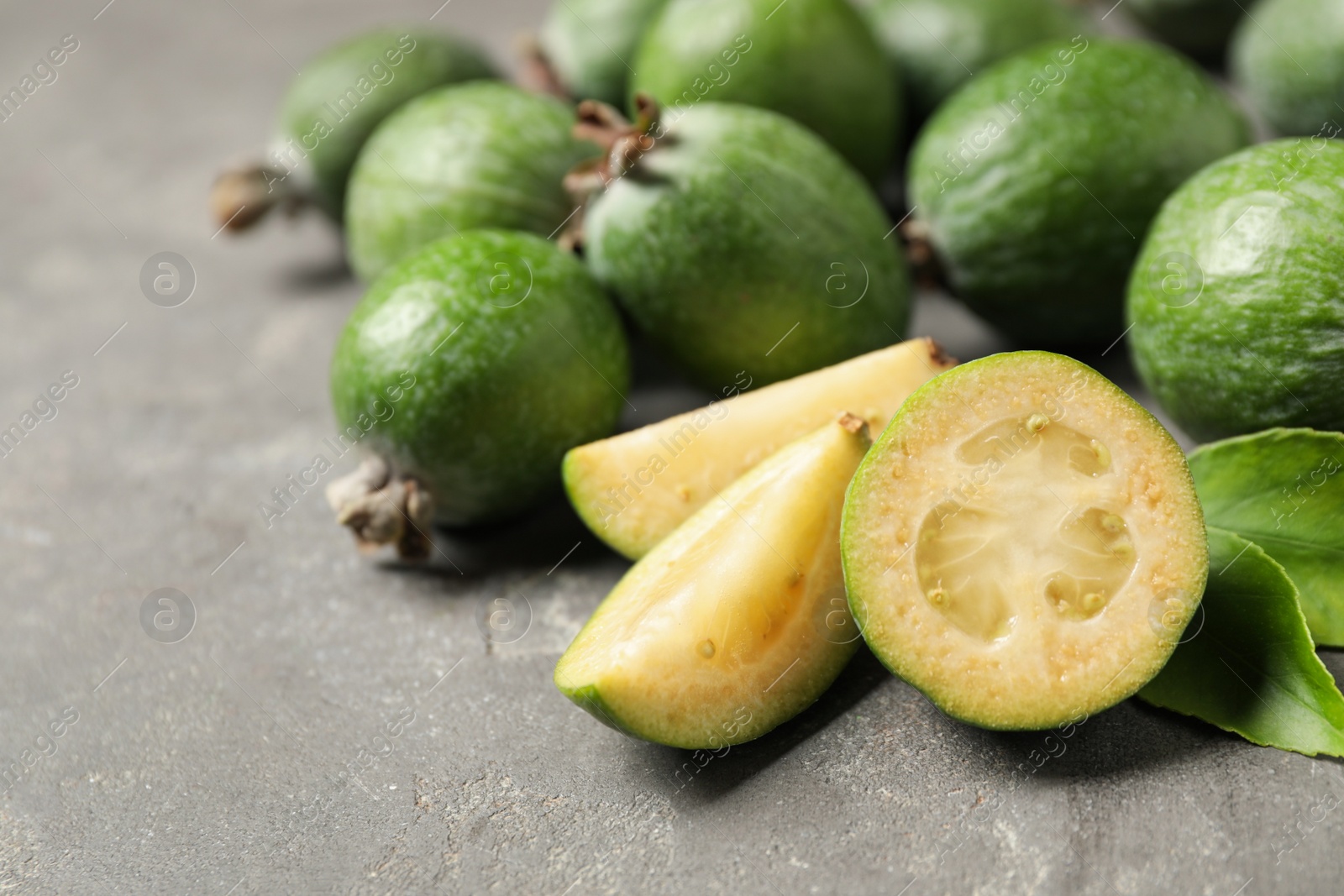 Photo of Fresh green feijoa fruits on grey table, closeup. Space for text