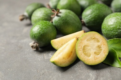 Photo of Fresh green feijoa fruits on grey table, closeup. Space for text