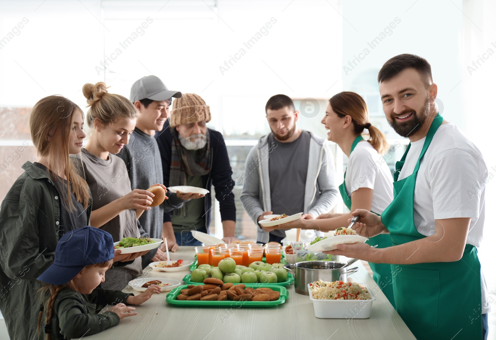 Photo of Volunteer with colleague giving food to poor people indoors