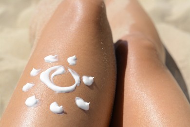 Photo of Sun drawn with sunscreen on woman's leg at beach, closeup