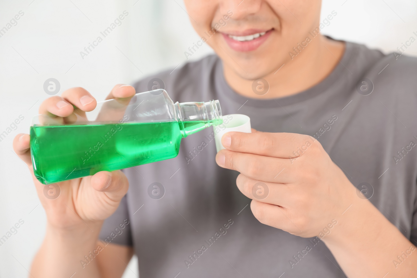 Photo of Man pouring mouthwash from bottle into cap, closeup. Teeth care