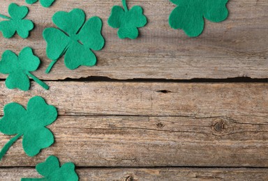 Photo of St. Patrick's day. Decorative clover leaves on wooden background, flat lay. Space for text