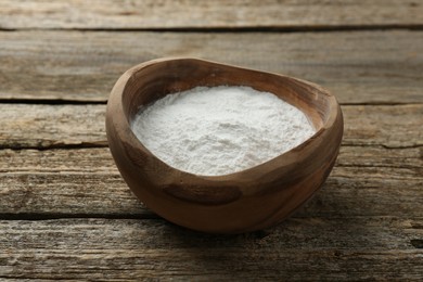 Photo of Baking powder in bowl on wooden table