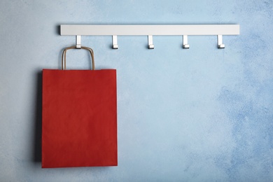 Photo of Rack with paper shopping bag on color wall