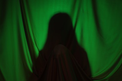 Photo of Silhouette of creepy ghost behind dark green cloth