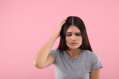 Photo of Emotional woman examining her hair and scalp on pink background, space for text. Dandruff problem