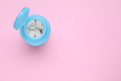 Photo of Jar with chewing gums on pink background, top view. Space for text